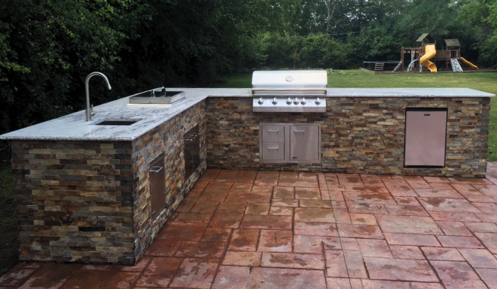 Outdoor kitchen island with a Lion Gas Grill, built-in refrigerator, and large countertop, finished with stackstone for a sleek and durable outdoor entertaining space.