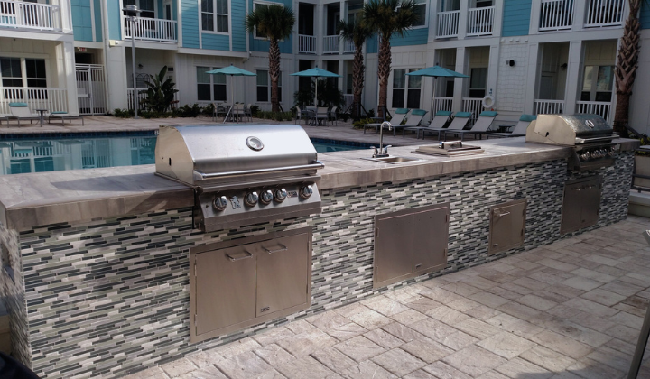 Sleek outdoor kitchen island in an apartment complex common area with a Lion Gas Grill, refrigerator, and spacious countertop, perfect for social gatherings