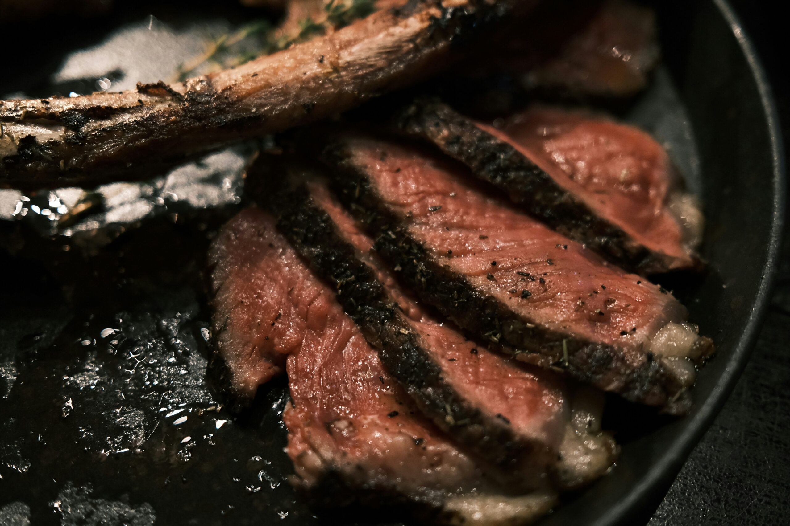 Sliced rotisserie prime rib on a gas grill showing a perfect medium-rare pink interior and dark herb crust