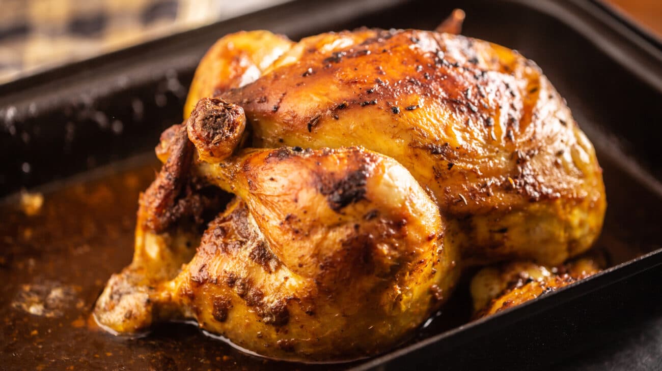 barbecued whole chicken with crispy golden crust skin on paper, view from above, close-up