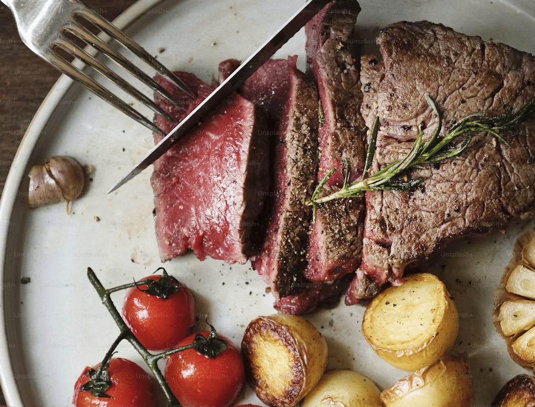 Thick steaks roasting inside a premium Lion gas grill with independent burner controls