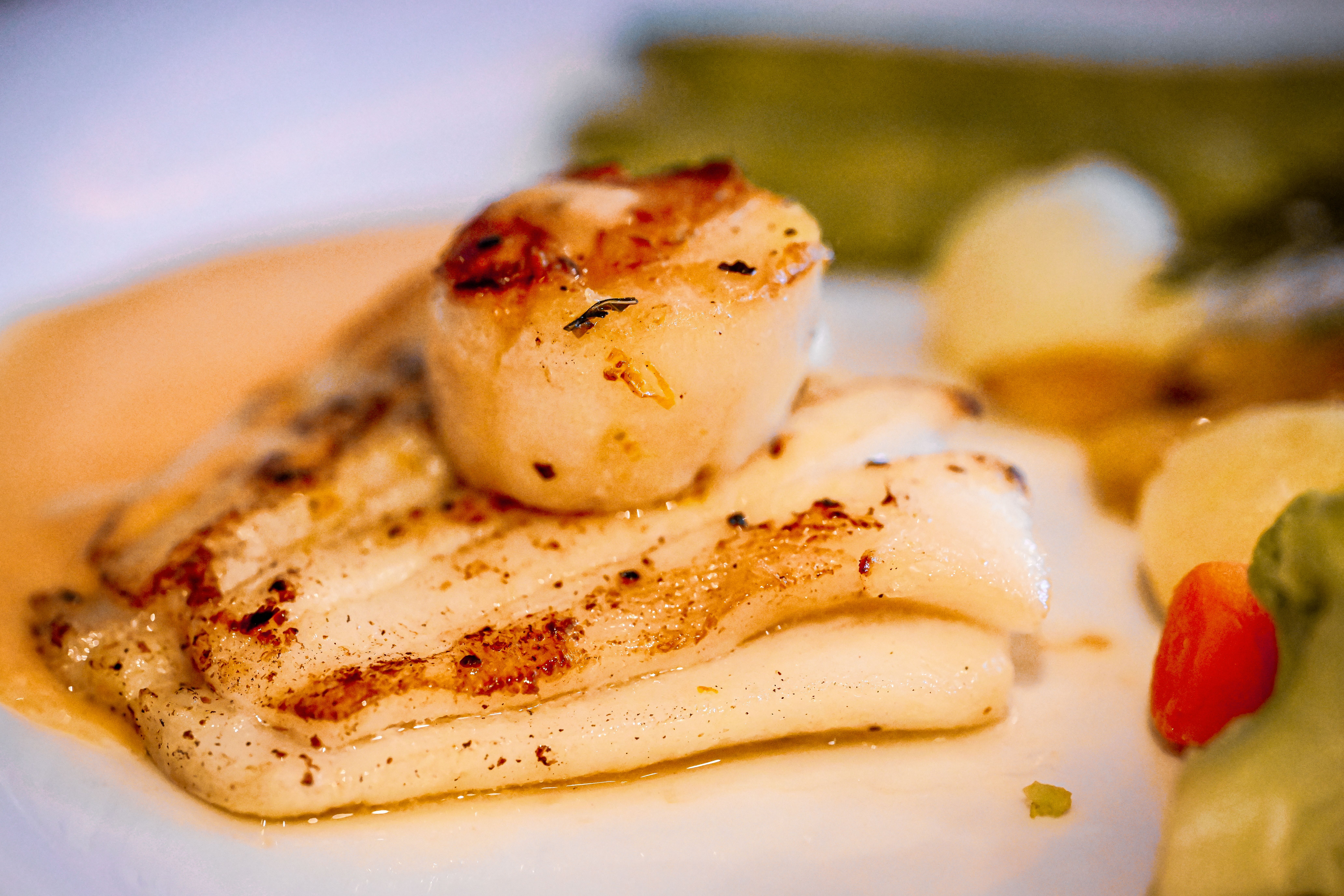 Finished seared scallops with golden crust plated with vegetables from a Lion gas grill sear burner