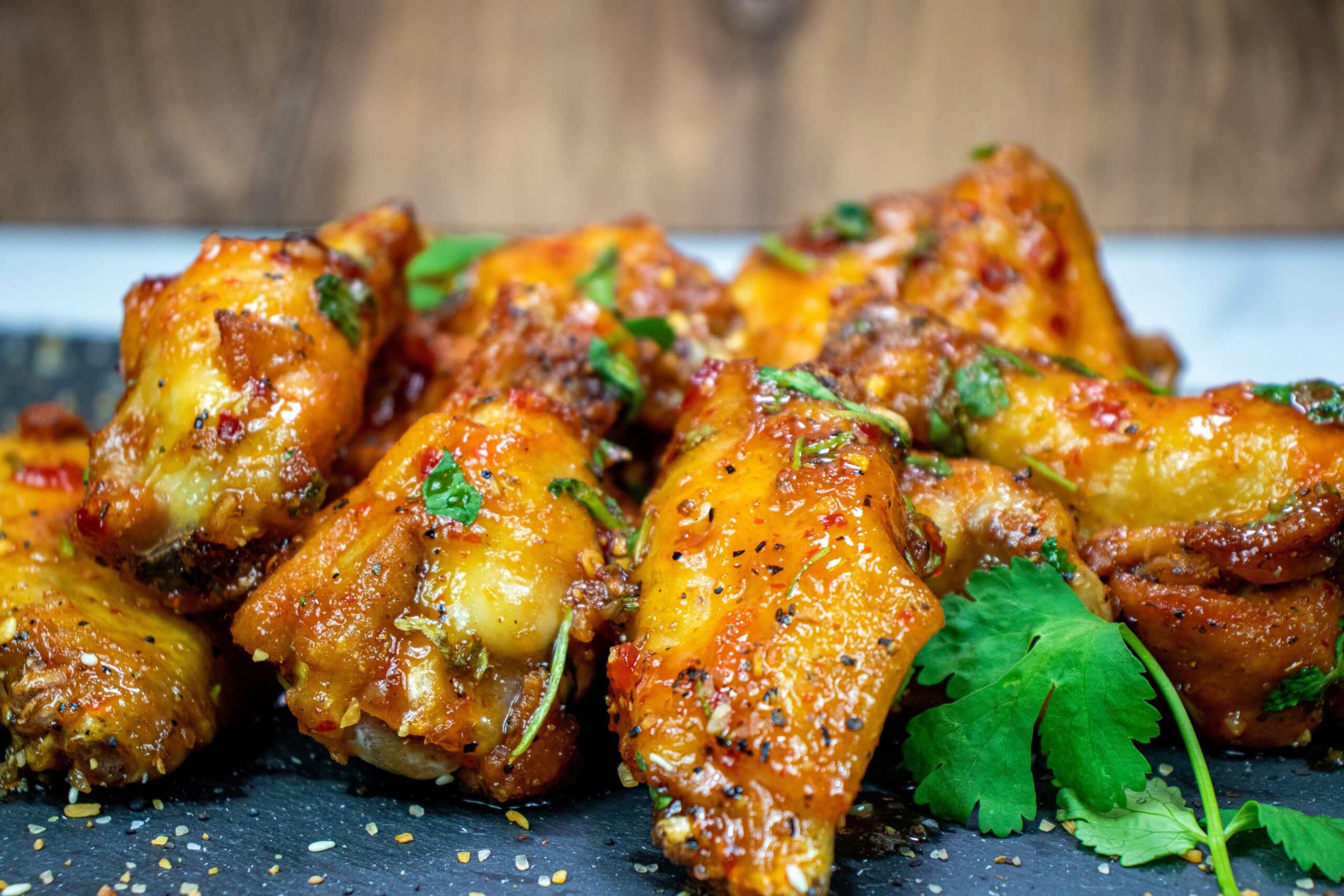 Platter of crispy wings on gas grill tossed in classic buffalo sauce