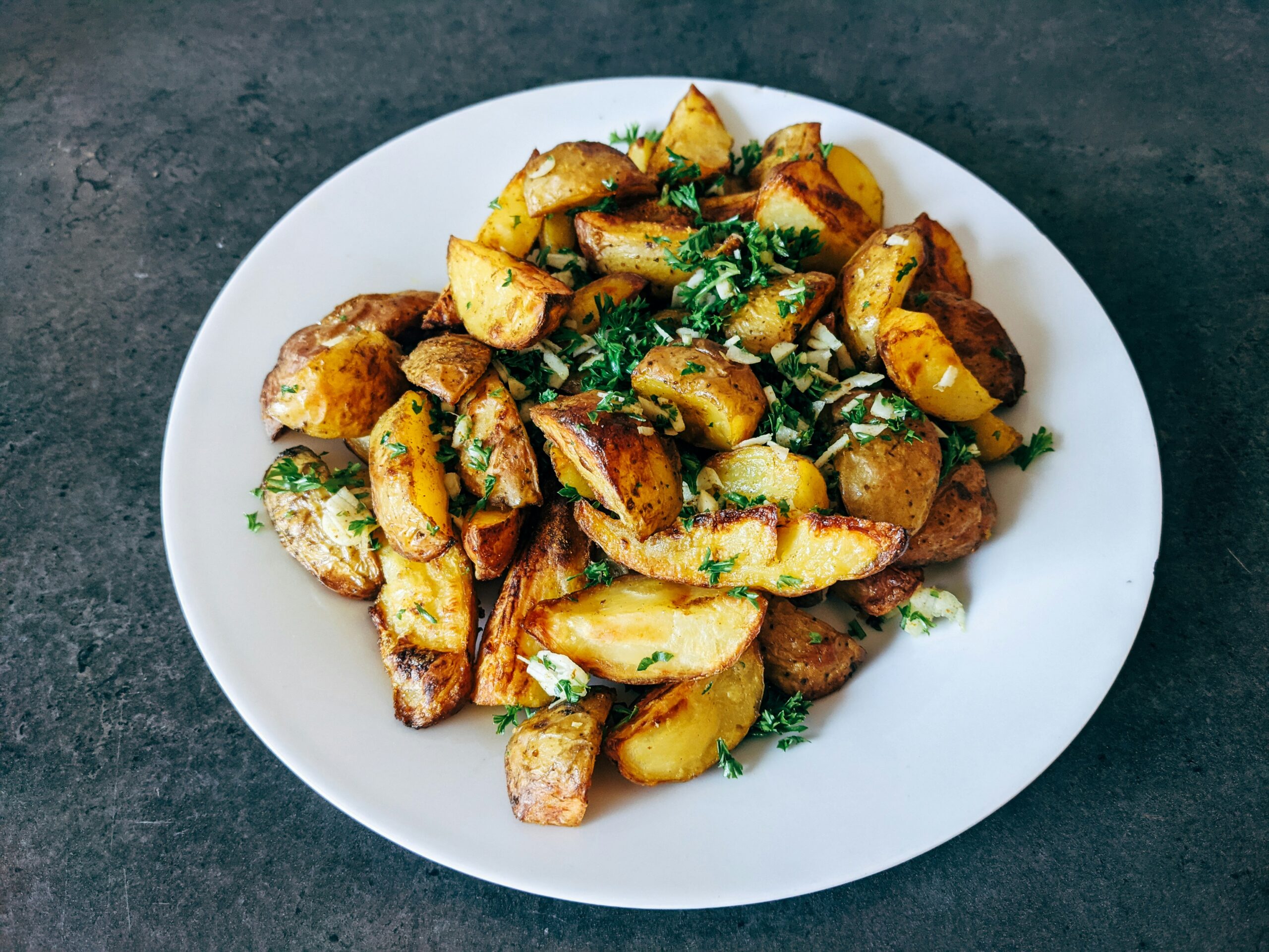 Finished crispy golden rotisserie basket potatoes on a plate from a Lion gas grill outdoor cooking recipe