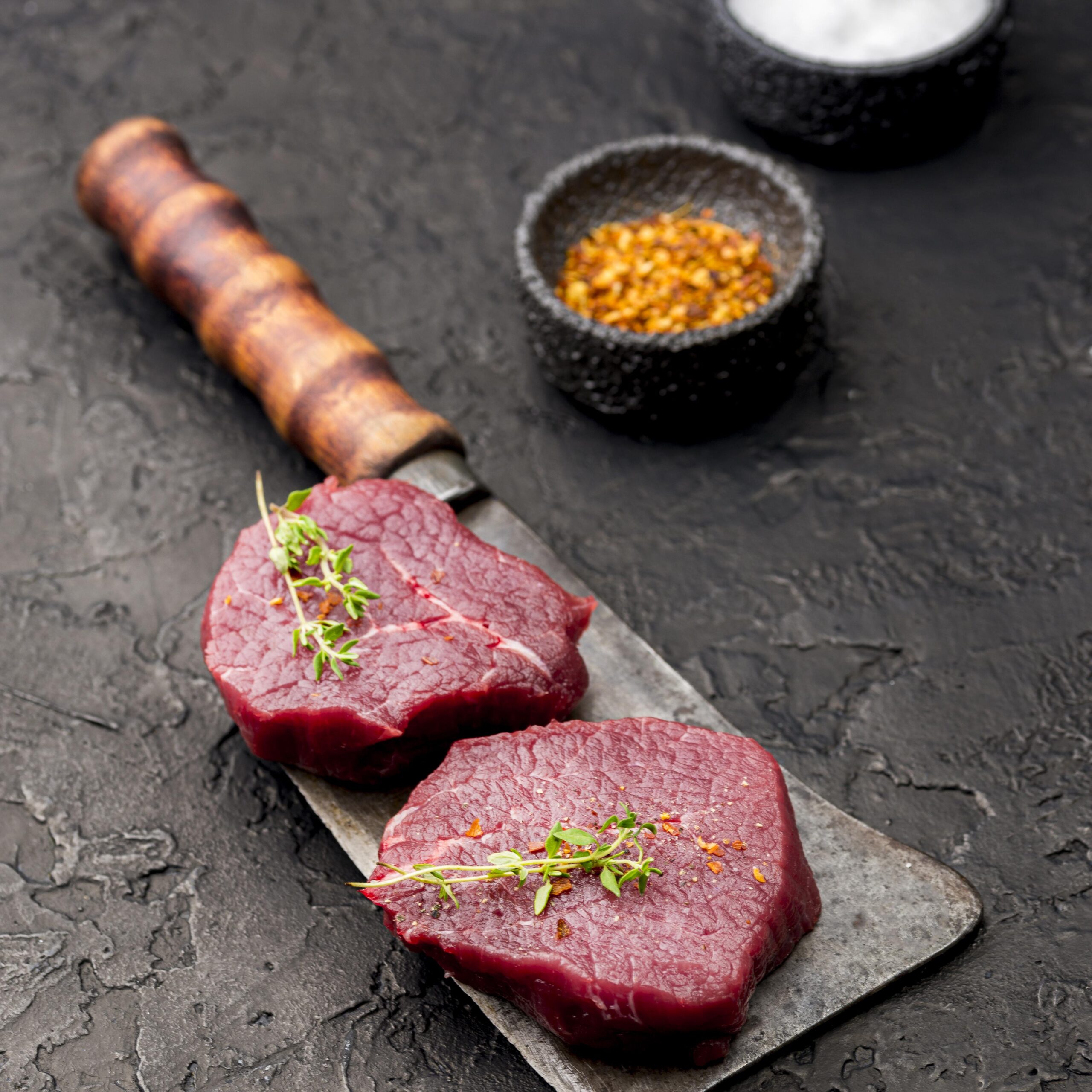 Raw filet mignon steaks on a cutting board ready for grilling on a Lion gas grill