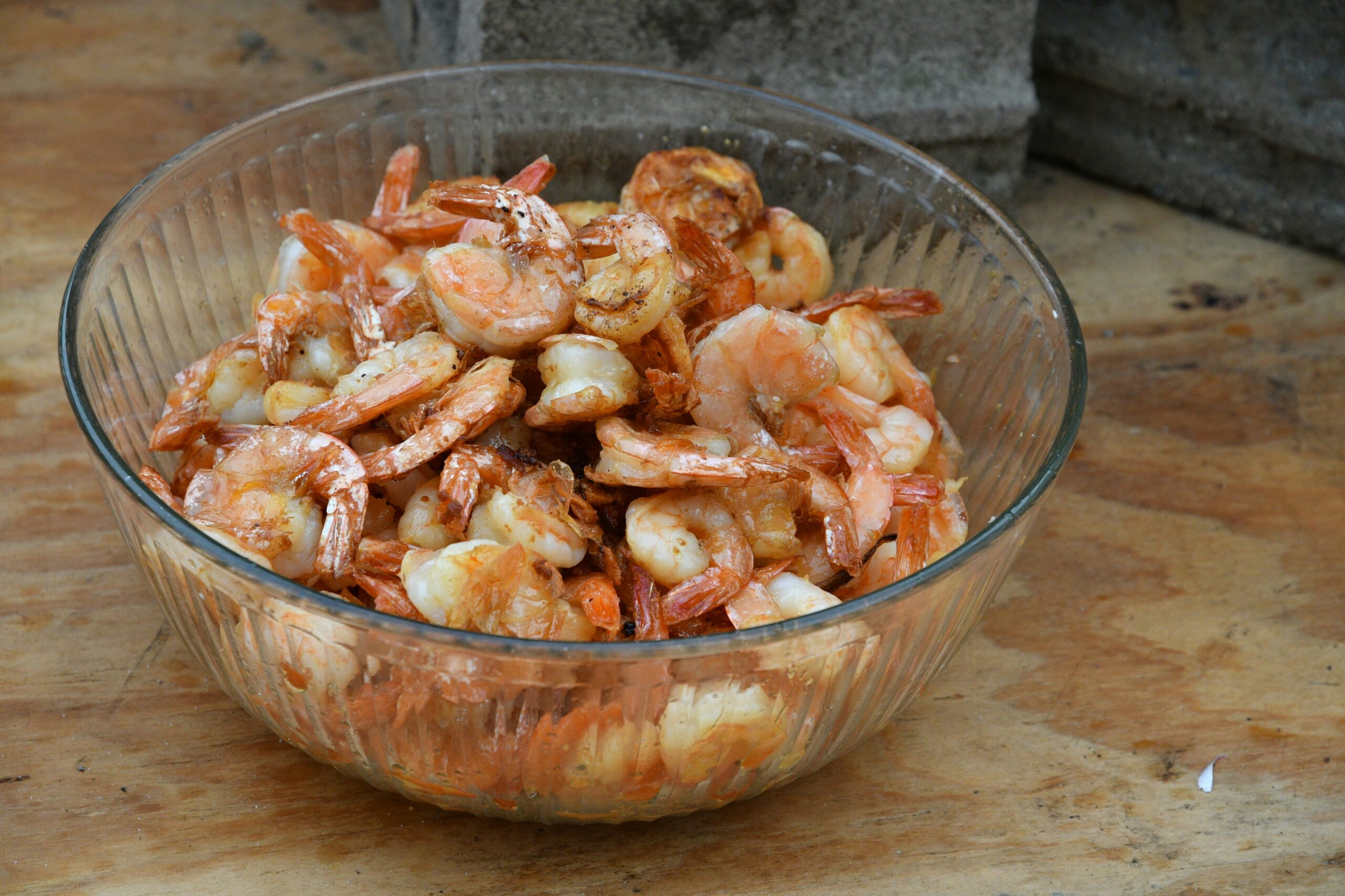 Raw shrimp in a glass bowl ready to marinate for rotisserie basket shrimp tacos on a Lion gas grill