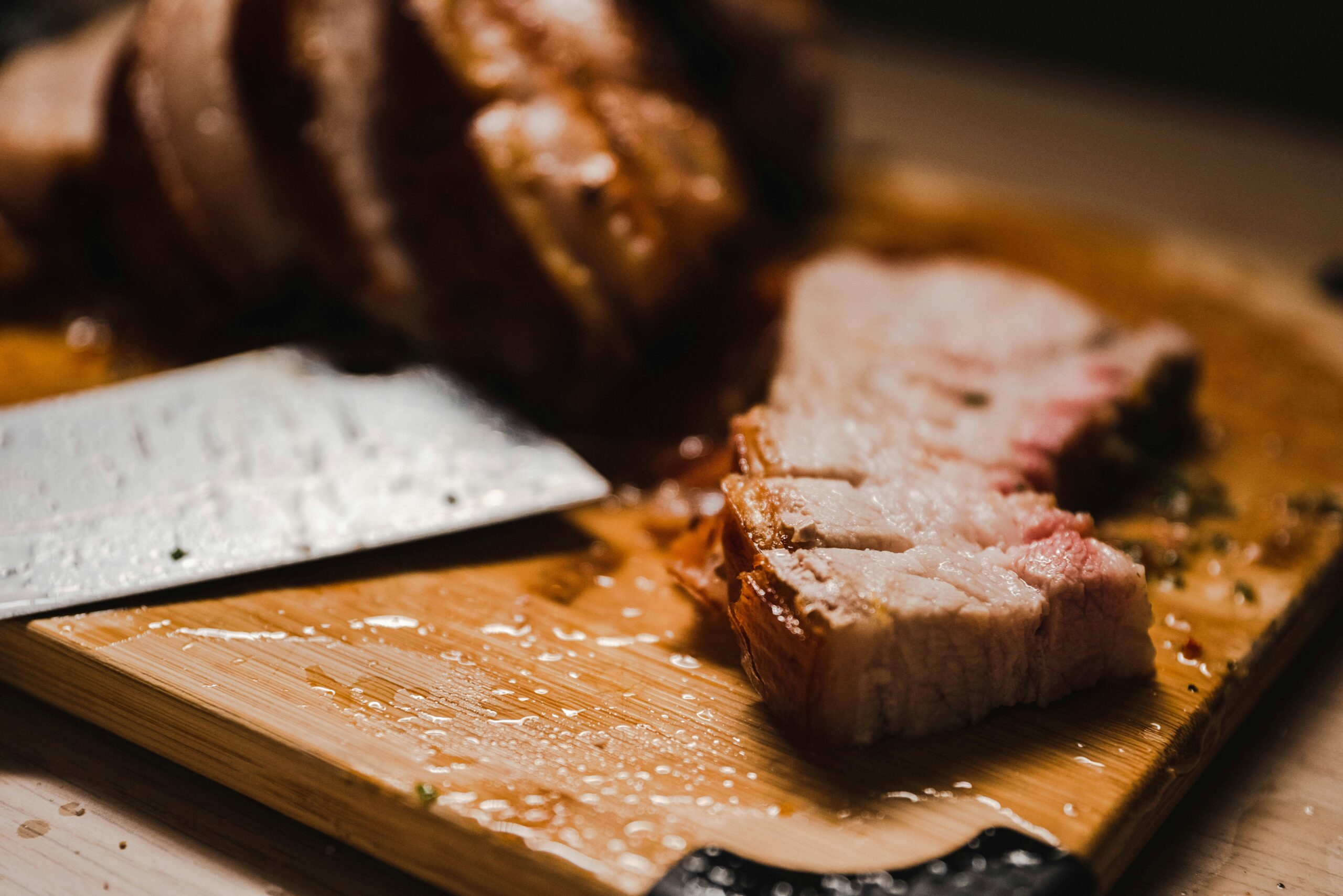 Sliced rotisserie pork loin with garlic herb crust on a cutting board from a Lion gas grill